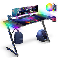 IMHome Gaming Desk with RGB LED Lights and Free Mouse Pad - 47" x 24" - Black Carbon Fiber Top/Black Frame-This high-performance foundation was engineered for gamers who demand a fusion of aggressive style and stability. This command centre features a premium carbon fibre surface paired with an integrated LED lighting system that transforms your room into an immersive gaming environment. Designed to maximize every inch of your workspace, the sleek Z-frame architecture provides a professional-grade platform 