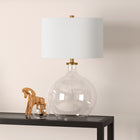 Hudson&Canal Laelia 24.75" Tall Table Lamp with Fabric Shade - Clear Glass/Brass/White-Handcrafted clear glass and brass finish is applied to the round glass base
