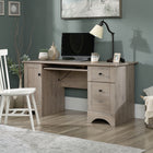 Sauder 59"W Sauder Select Desk - Laurel Oak- Desk top grommet hole for electrical cord access and organization